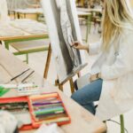artista-creativo-que-sienta-taburete-que-bosqueja-caballete-carreras de arte